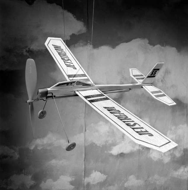 A toy wooden plane soaring through the clouds